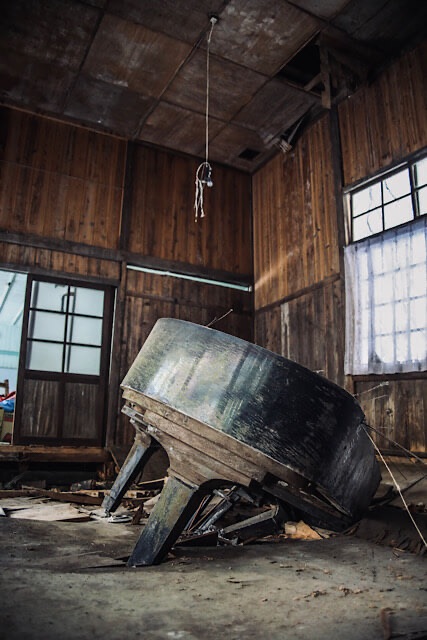 桑崎冬季分校の教室内。腐朽して完全に底が抜けた床板の間に、巨大な黒いグランドピアノが斜めに深く沈み込み、今にも床下に消えてしまいそうな様子。