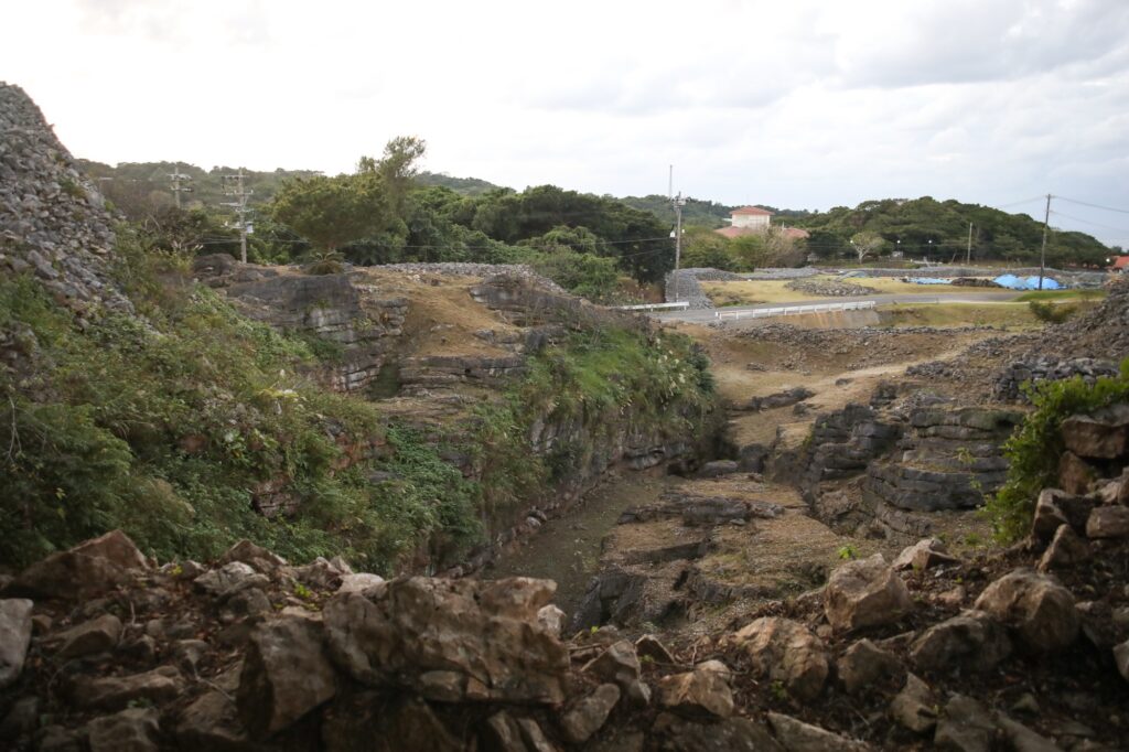 今帰仁城跡の天然の堀として機能していた、「カーザフ」と呼ばれる深い谷間の風景。幾層にも重なり、切り立った剥き出しの岩肌が続き、要塞としての圧倒的な威圧感と防御力を感じさせる。
