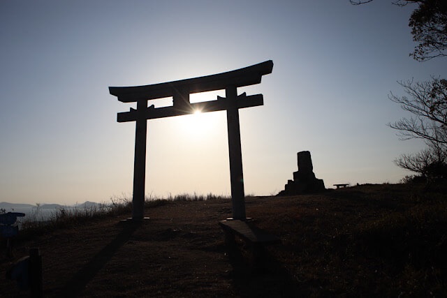龍王山の「天空の鳥居」。鳥居の真ん中から太陽が顔を出し、逆光で鳥居が力強いシルエットとなっている神々しい風景。