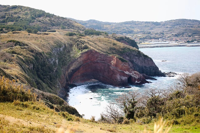 見島、観音平からの大パノラマ。赤い崖肌の巨大な断崖絶壁と海蝕洞が海に面している様子。