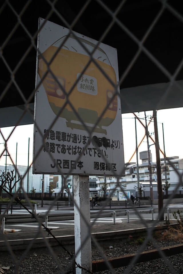 フェンスの向こう側に残る、JR西日本・鳳保線区が設置した「特急電車が通ります」と書かれた阪和貨物線の古い警告看板