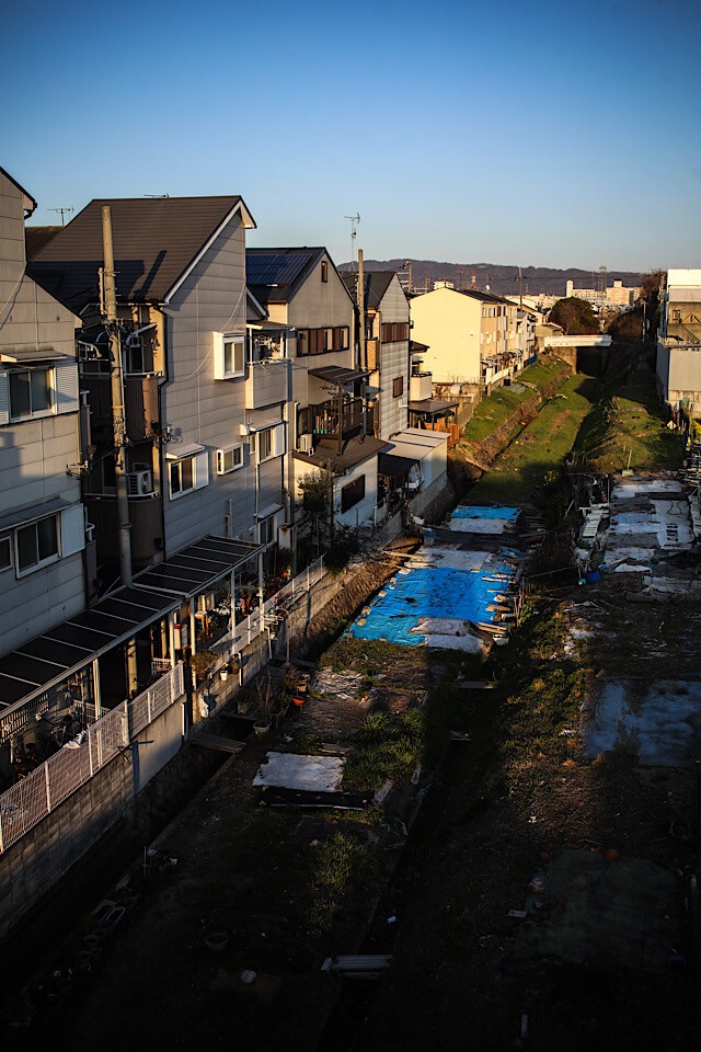 夕日に照らされる住宅街のすぐ脇を、周囲より一段低い溝のようになって大きくカーブしながら先へと続いている阪和貨物線の線路跡