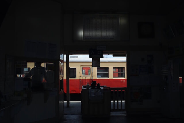 上総牛久駅の木造駅舎内観と改札口の向こうに見える小湊鐵道の車両。